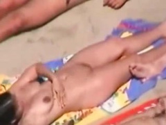 Impassive female on nude beach lets fellows spew on her